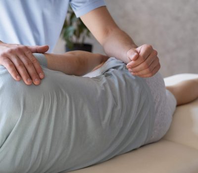 Close-up of a physiotherapist wearing a medical mask gently assisting a patient by supporting and guiding their leg during a physical therapy session
