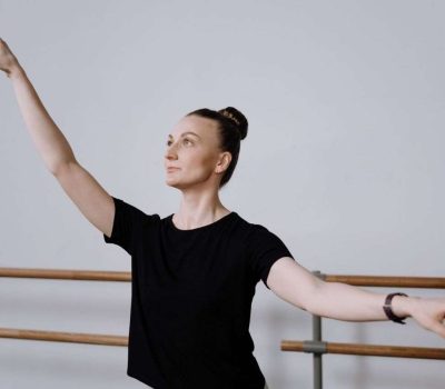 Ballet dancer in a black t-shirt practicing graceful arm positions in a dance studio.